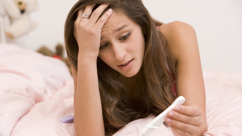 Teenage Girl Lying On Her Bed With A Pregnancy Test